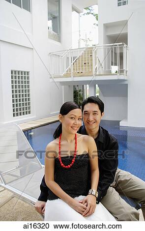 Couple sitting by poolside, looking at camera View Large Photo Image Stock Image - Couple sitting by poolside, looking at camera . Fotosearch