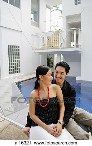 Couple sitting by poolside, looking at each other View Large Photo Image Stock Image - Couple sitting by poolside, looking at each other . Fotosearch