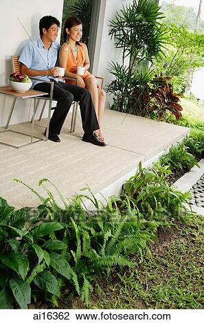 Couple sitting on patio having coffee, looking away View Large Photo Image Stock Image - Couple sitting on patio having coffee, looking away . Fotosearch