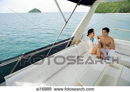 Stock Photo - Couple sitting on stern of yacht . Fotosearch