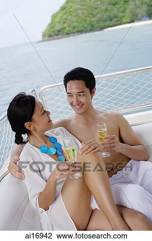 Couple sitting on stern of yacht, with champagne glasses View Large Photo Image Stock Image - Couple sitting on stern of yacht, with champagne glasses . Fotosearch