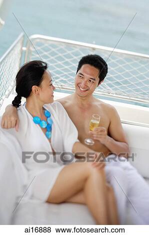 Couple sitting on yacht, side by side, man holding drink View Large Photo Image Stock Photo - Couple sitting on yacht, side by side, man holding drink . Fotosearch
