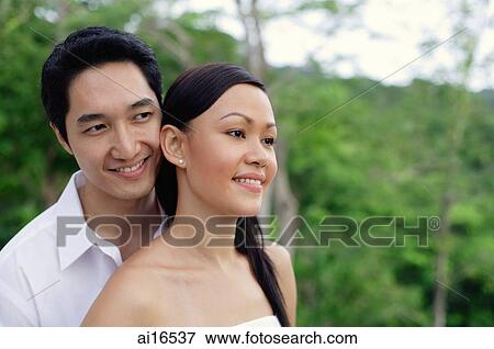 Stock Photo - Couple smiling, looking away, head shot . Fotosearch