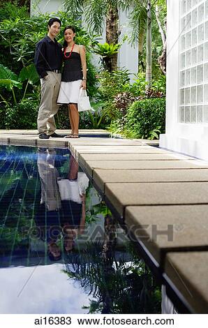 Couple standing by swimming pool, smiling at camera View Large Photo Image Stock Image - Couple standing by swimming pool, smiling at camera . Fotosearch