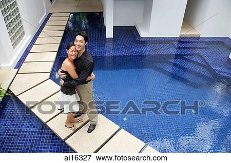 Couple standing by swimming pool, embracing, looking up at camera View Large Photo Image Stock Photo - Couple standing by swimming pool, embracing, looking up at camera . Fotosearch