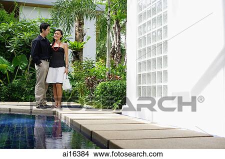 Couple standing next to swimming pool View Large Photo Image Picture - Couple standing next to swimming pool. Fotosearch