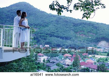 Couple standing on balcony looking out at view View Large Photo Image Stock Image - Couple standing on balcony looking out at view . Fotosearch