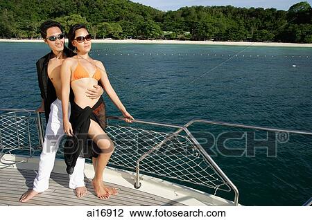 Couple standing on boat deck, man with arms around woman View Large Photo Image Stock Image - Couple standing on boat deck, man with arms around woman . Fotosearch