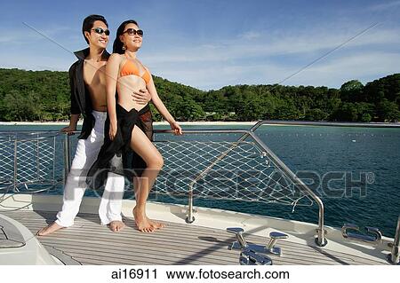 Stock Image - Couple standing on boat deck . Fotosearch