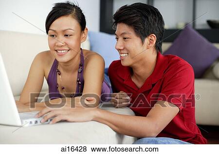 Couple using laptop in living room View Large Photo Image Stock Photo - Couple using laptop in living room. Fotosearch