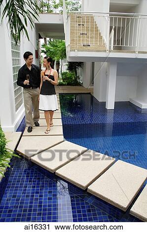 Stock Image - Couple walking by swimming pool . Fotosearch