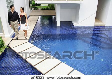 Couple walking hand in hand by swimming pool View Large Photo Image Stock Image - Couple walking hand in hand by swimming pool. Fotosearch