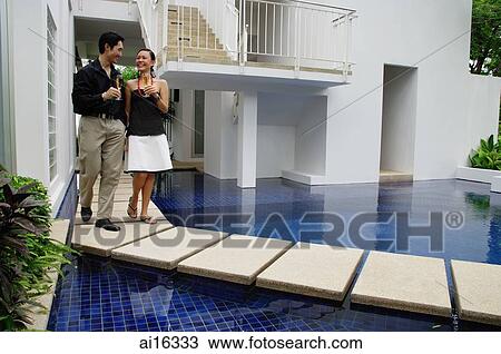 Couple walking next to swimming pool, champagne glasses in hand View Large Photo Image Stock Image - Couple walking next to swimming pool, champagne glasses in hand . Fotosearch
