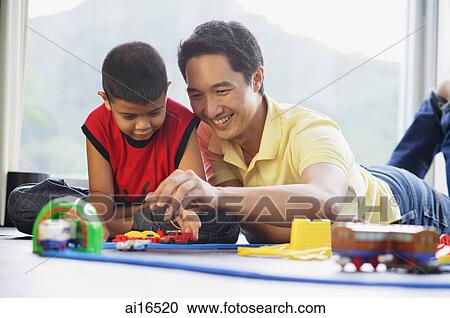 Father and son side by side on floor, playing with train set View Large Photo Image Stock Image - Father and son side by side on floor, playing with train set . Fotosearch