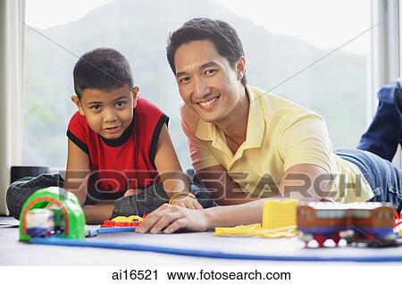 Father and son side by side on floor, smiling at camera, train set in front of them View Large Photo Image Stock Image - Father and son side by side on floor, smiling at camera, train set in front of them . Fotosearch