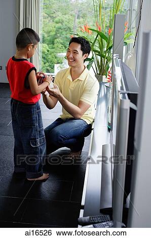 Stock Photograph - Father facing son, passing son a toy . Fotosearch