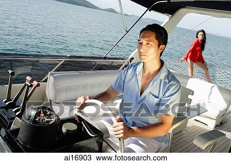 Man at helm of yacht, woman in the background View Large Photo Image Stock Image - Man at helm of yacht, woman in the background . Fotosearch
