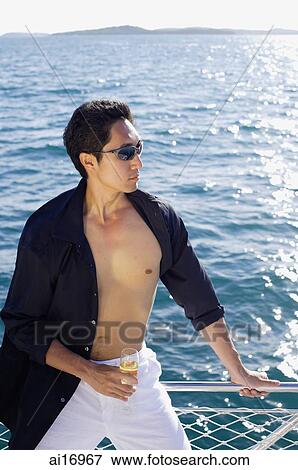 Man on boat, leaning on railing, drink in hand, portrait View Large Photo Image Stock Photo - Man on boat, leaning on railing, drink in hand, portrait . Fotosearch