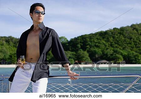 Man on boat, leaning on railing, drink in hand View Large Photo Image Stock Photography - Man on boat, leaning on railing, drink in hand . Fotosearch