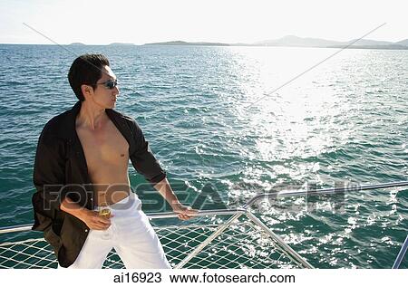 Man on boat, standing next to railing, drink in hand View Large Photo Image Stock Image - Man on boat, standing next to railing, drink in hand. Fotosearch