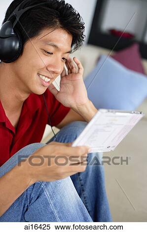 Man sitting on sofa, headphones on, listening to music View Large Photo Image Stock Photography - Man sitting on sofa, headphones on, listening to music. Fotosearch
