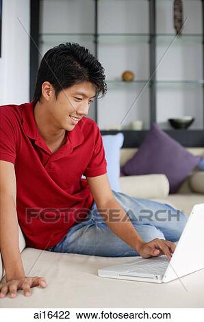 Man sitting on sofa, using laptop View Large Photo Image Stock Image - Man sitting on sofa, using laptop . Fotosearch