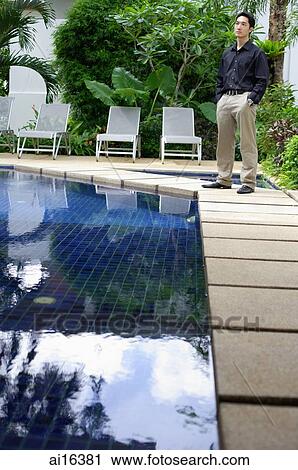Man standing by swimming pool, hands in pocket View Large Photo Image Stock Image - Man standing by swimming pool, hands in pocket . Fotosearch