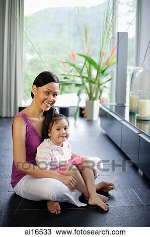 Stock Image - Mother and daughter smiling at camera, portrait. Fotosearch