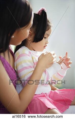 Mother with young girl on her lap, side view View Large Photo Image Stock Photograph - Mother with young girl on her lap, side view. Fotosearch