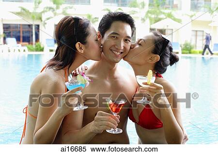 Two woman dressed in bikinis, kissing man View Large Photo Image Stock Photography - Two woman dressed in bikinis, kissing man . Fotosearch