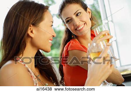 Two women holding wine glasses, smiling at each other View Large Photo Image Stock Photo - Two women holding wine glasses, smiling at each other. Fotosearch