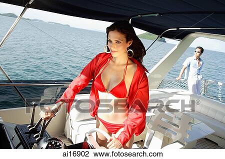 Woman at helm of yacht, man in the background View Large Photo Image Stock Image - Woman at helm of yacht, man in the background . Fotosearch