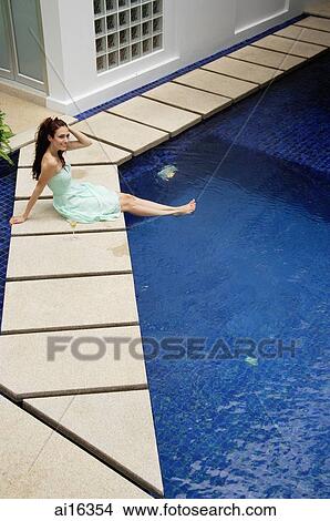 Woman in green dress sitting by pool, smiling View Large Photo Image Picture - Woman in green dress sitting by pool, smiling . Fotosearch