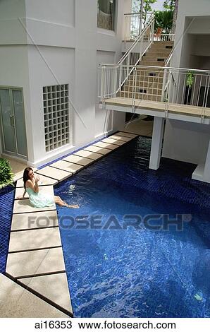 Stock Image - Woman in green dress sitting by pool . Fotosearch