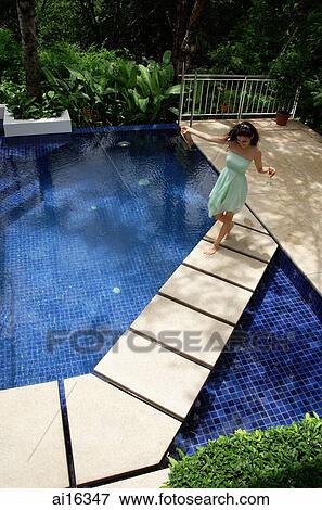Stock Photo - Woman in green dress walking across swimming pool . Fotosearch