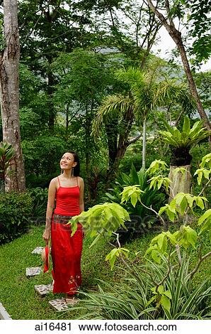 Woman in red dress, walking through garden View Large Photo Image Stock Image - Woman in red dress, walking through garden . Fotosearch