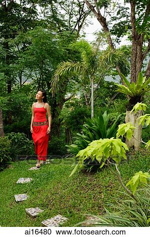Woman in red outfit, walking through garden View Large Photo Image Stock Image - Woman in red outfit, walking through garden . Fotosearch