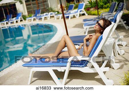 Woman in swimwear, wearing sunglasses, sitting on deck chair View Large Photo Image Stock Image - Woman in swimwear, wearing sunglasses, sitting on deck chair . Fotosearch