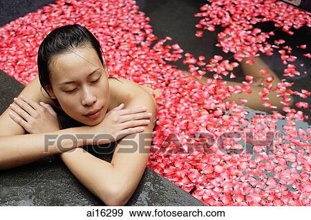 Woman leaning at edge of tub, flowers floating in water View Large Photo Image Stock Photo - Woman leaning at edge of tub, flowers floating in water. Fotosearch