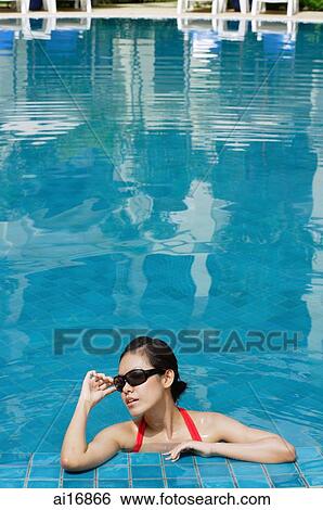 Woman leaning on edge of swimming pool, adjusting sunglasses View Large Photo Image Stock Photograph - Woman leaning on edge of swimming pool, adjusting sunglasses . Fotosearch