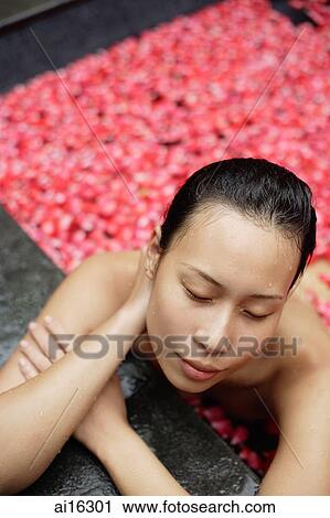 Woman leaning on edge of tub filled with floating rose petals, eyes closed View Large Photo Image Stock Image - Woman leaning on edge of tub filled with floating rose petals, eyes closed . Fotosearch