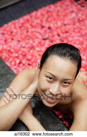 Woman leaning on edge of tub filled with floating rose petals, smiling at camera View Large Photo Image Stock Image - Woman leaning on edge of tub filled with floating rose petals, smiling at camera . Fotosearch