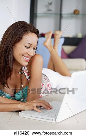 Woman lying on sofa, using laptop View Large Photo Image Stock Image - Woman lying on sofa, using laptop . Fotosearch