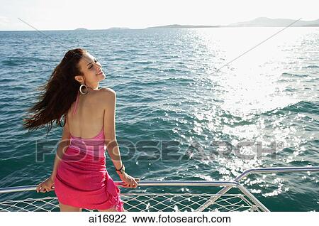 Woman on boat, standing next to railing, enjoying breeze View Large Photo Image Stock Image - Woman on boat, standing next to railing, enjoying breeze . Fotosearch