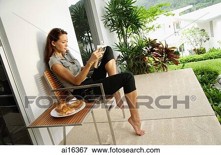 Stock Photo - Woman reading book on patio . Fotosearch