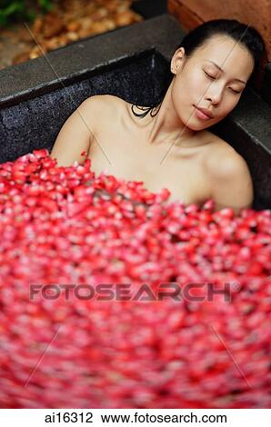 Woman relaxing in tub, eyes closed, petals floating around her View Large Photo Image Stock Image - Woman relaxing in tub, eyes closed, petals floating around her . Fotosearch
