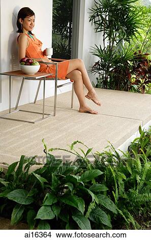 Woman sitting and having coffee on patio View Large Photo Image Picture - Woman sitting and having coffee on patio . Fotosearch