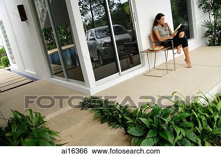 Woman sitting on patio, reading magazine View Large Photo Image Stock Photograph - Woman sitting on patio, reading magazine . Fotosearch
