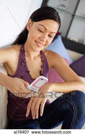 Woman sitting on sofa, using mobile phone View Large Photo Image Stock Photo - Woman sitting on sofa, using mobile phone . Fotosearch