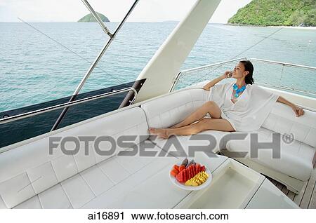 Stock Image - Woman sitting on stern of yacht . Fotosearch